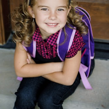 A young girl wearing a backpack is ready to start school.