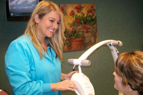 Female dental professional showing a patient their in-office Zoom! Teeth Whitening equipment.
